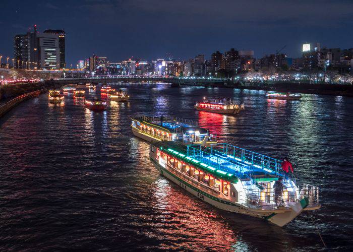 A procession of yakatabune floating down the Sumida River.
